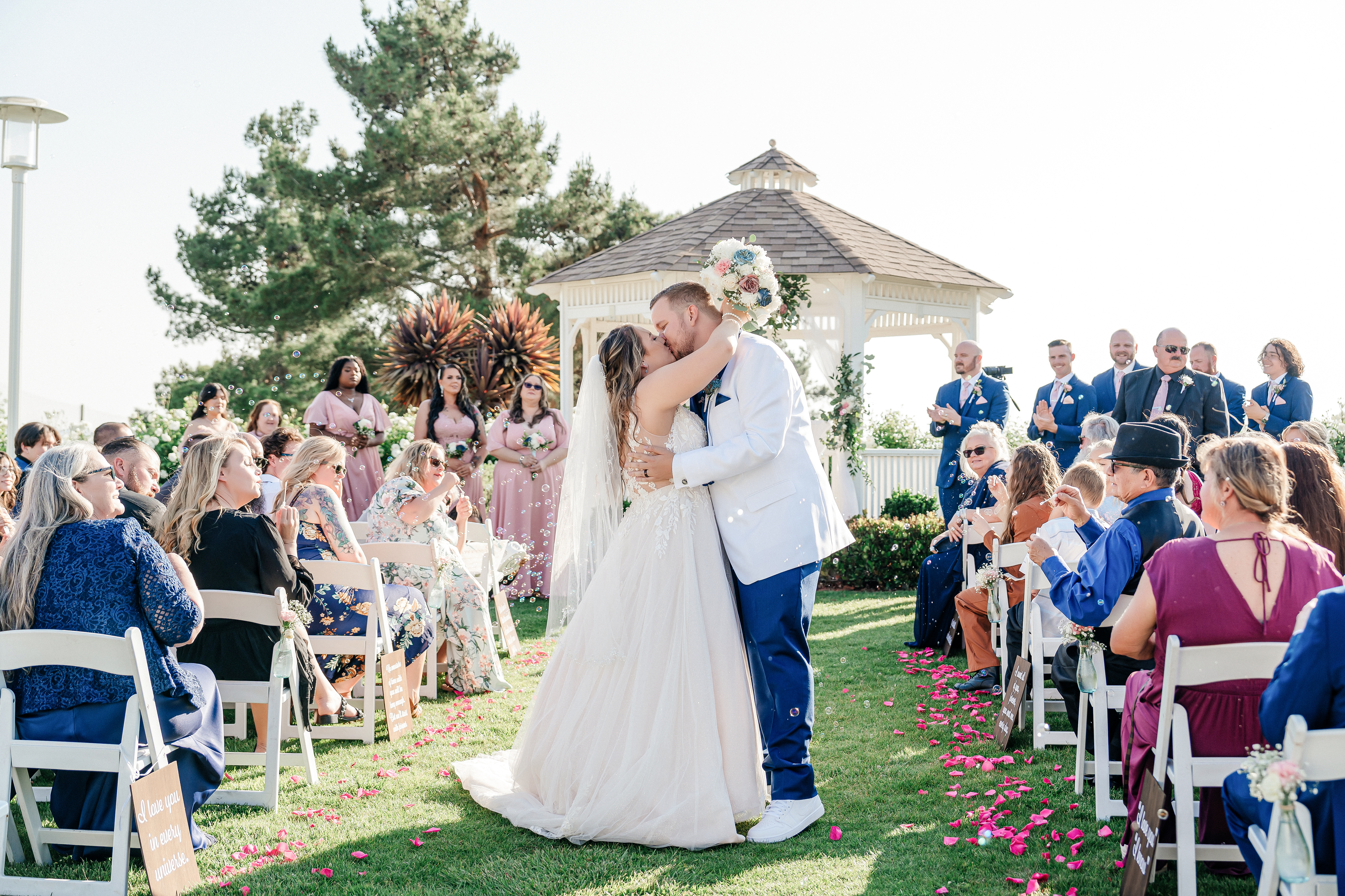 Aladdin Films wedding couple kissing at the altar surrounded by bubbles and bridal party